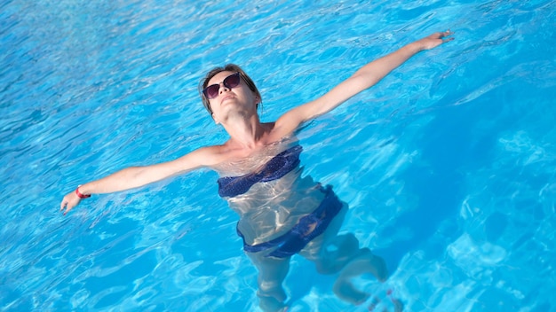 수영장 물에서 편안한 선글라스에 행복 한 아름 다운 여자