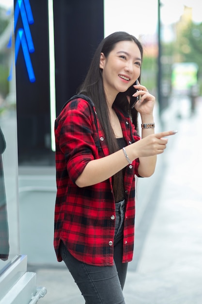 街の通りを歩いて、彼女の友人と電話で話している幸せな美しい女性