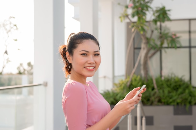 屋外でスマートフォンを使用して幸せな美しい女性