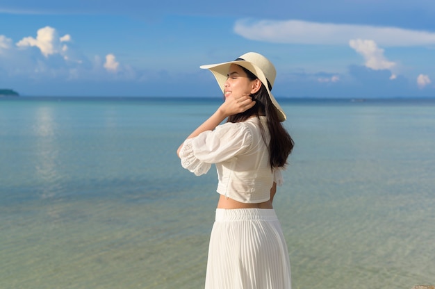 A happy beautiful woman in white dress enjoying and relaxing on the beach