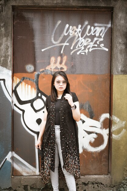 Happy Beautiful Young Asian woman wearing authentic dress posing front of abstract mural