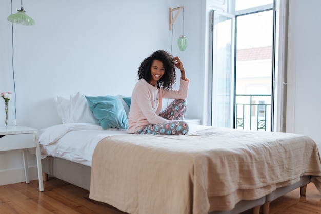 Happy beautiful young black woman relaxed sitting in the bed