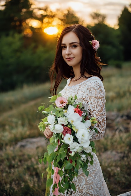 Happy beautiful young bride outside on a summer meadow at the sunset, close-up