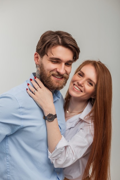 Happy beautiful young couple in fashionable clothes Beautiful happy redhead woman with smile and handsome hipster man with tattoo and beard