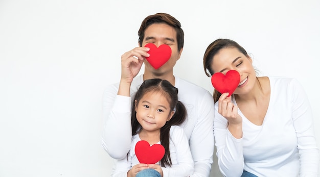 Happy beautiful young family father, mother and daughter with red hearts smiling