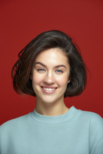 Happy beautiful young girl smiling with perfect shining white smile on red background dental clinic