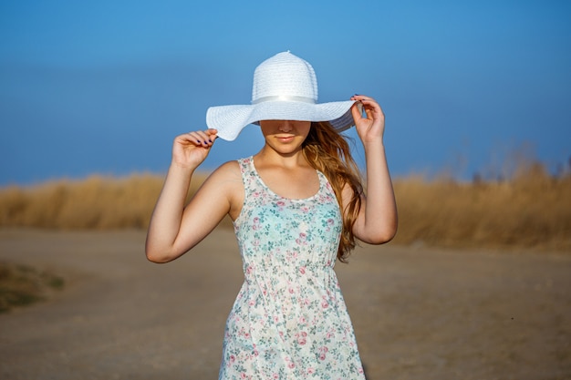 写真 晴れた日に自然の背景に帽子と幸せな美しい若い女の子。