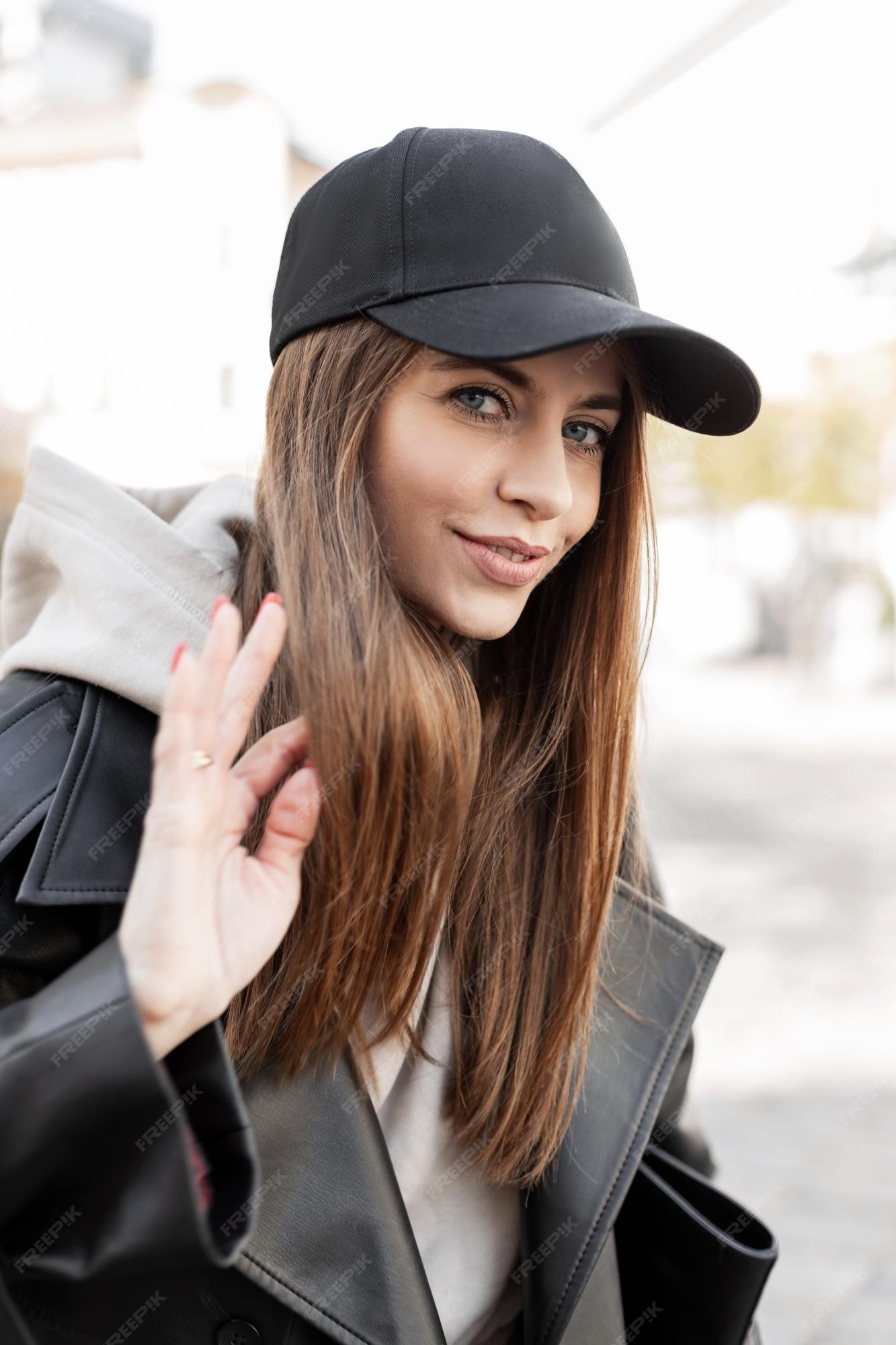 Premium Photo | Happy beautiful young hipster girl with a black mockup cap  in a trendy casual urban outfit with leather jacket and hoodie walking on  the street on a sunny day