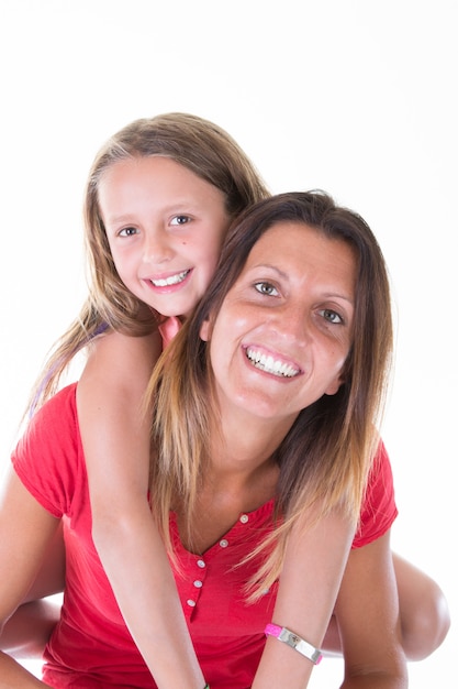 Happy beautiful young mother holding back her little cheerful daughter isolated on white