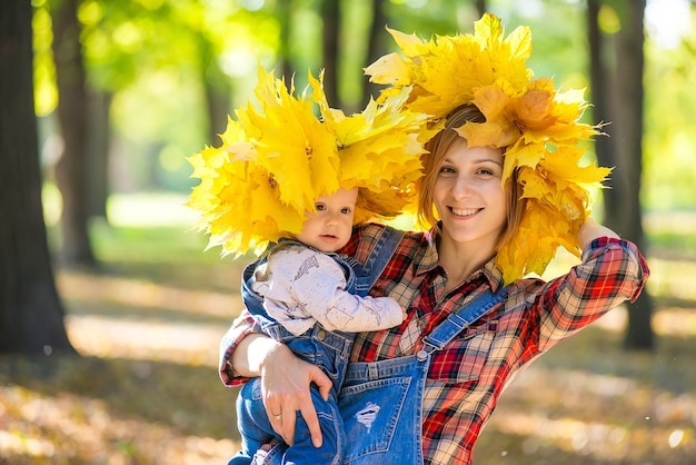 Happy beautiful young mother holding a child walking in the park in autumn.