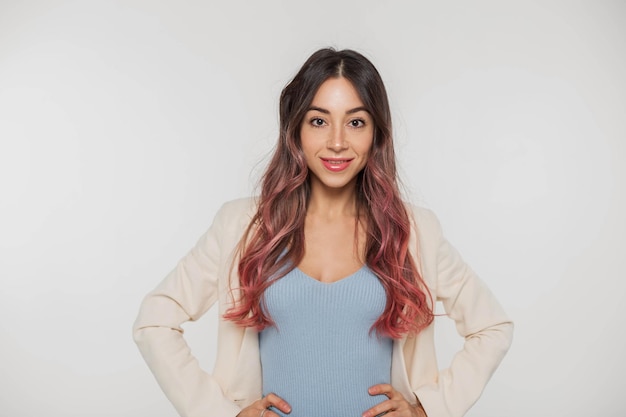 Happy beautiful young stylish woman with freckles and pink hair in trendy fashion clothes with a top and a blazer on a white background