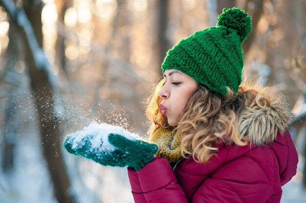 Bella giovane donna felice che soffia i fiocchi di neve