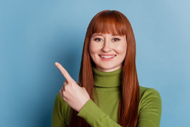 Счастливая красивая молодая женщина указывает пустое пространство на синем фоне с указательными пальцами