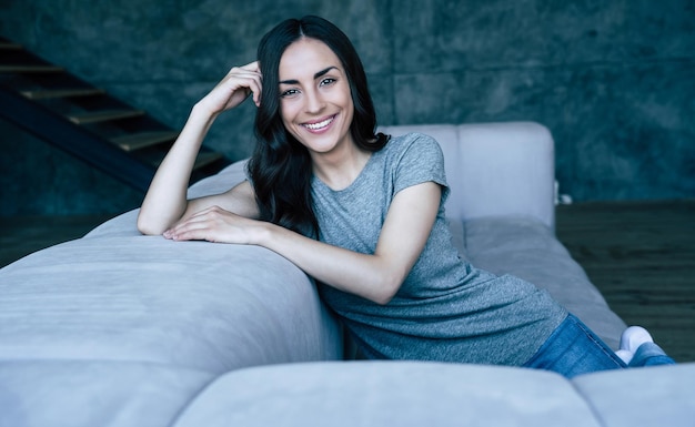 Happy beautiful young woman relaxing on the couch at home and smiling