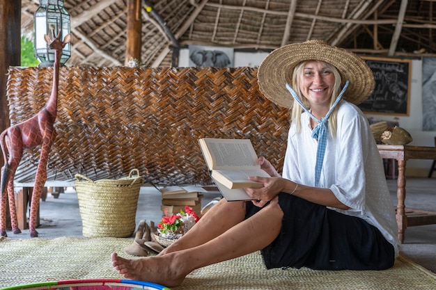 Happy beautiful young woman in a straw hat on a tropical beach close up portrait