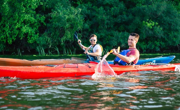 Happy best friends having fun on a kayaks. kayaking on the\
river. two friends in a boat sailing in the river