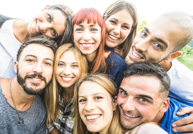 Happy best friends taking selfie outdoors with desaturated backlighting