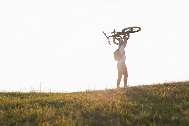 Счастливый велосипедист празднует победу, держа велосипед над собой Концепция спортивного успеха