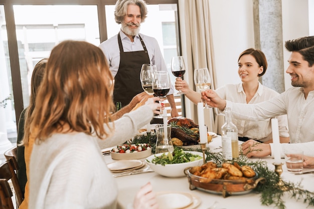 Happy big family celebrating Christmas together at home, having traditional Christmas dinner, smiling grandfather holding roasted turkey