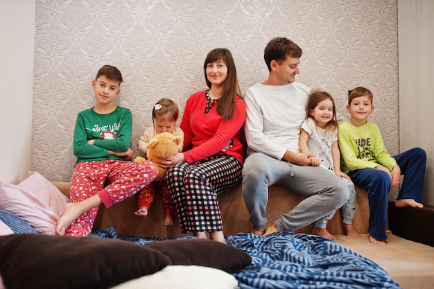 La grande famiglia felice si diverte insieme in camera da letto. grande concetto di mattina in famiglia. quattro bambini con i genitori indossano il pigiama a letto a casa.