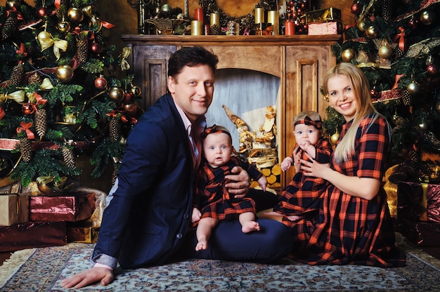 A happy big family with their children in the New Year's interior of the house by the fireplace next to the Christmas tree