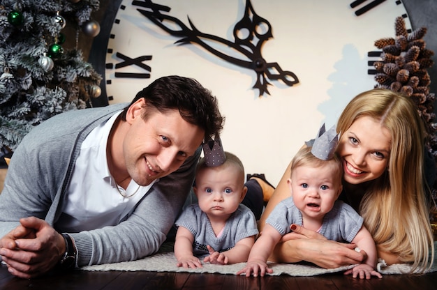 Una grande famiglia felice con bambini gemelli nell'interno della casa di capodanno sullo sfondo di un grande orologio