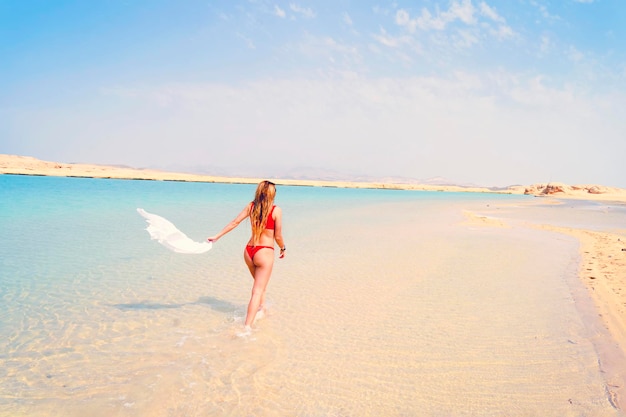 Happy bikini woman running of joy and success on perfect sand beach on caribbean tropical vacation Holiday girl with sexy slim suntan body running of freedom happiness