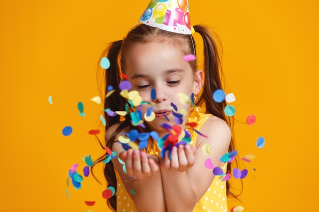 Happy birthday child girl with confetti on yellow background