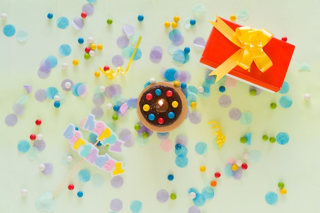 Happy Birthday concept. Cake, gift box, confetti and party items scattered on the table. Top view