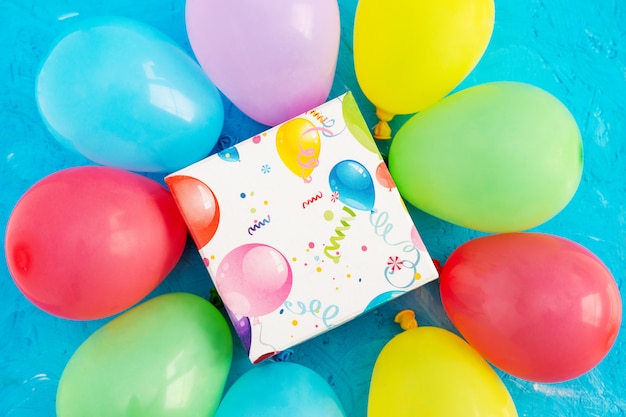 Happy birthday concept. Colored balloons and gift box on a blue background, copy space