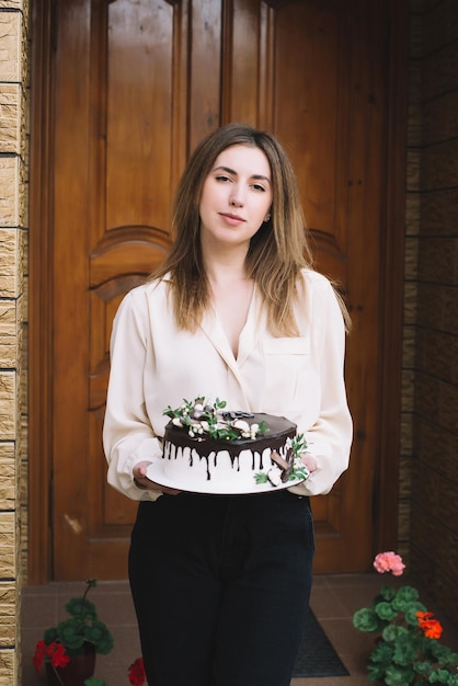 Happy birthday to me Excited gorgeous woman holding a delicious cake and smiling while celebrating her birthday party on the outside