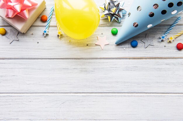 Happy birthday or party background.  Flat Lay wtih birthday hats, confetti and ribbons on white wooden background. Top View.  Copy space.