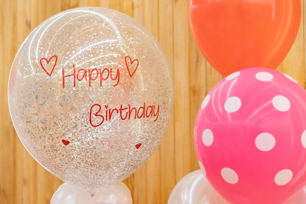 A happy birthday text on the balloon for gift in the birthday party standing in front of wood background.