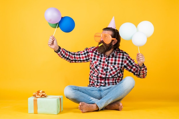 Happy birthday to you bearded mature man celebrate birthday party cheerful man in bday hat hold holiday balloons gifts and presents concept have a happy holiday party time