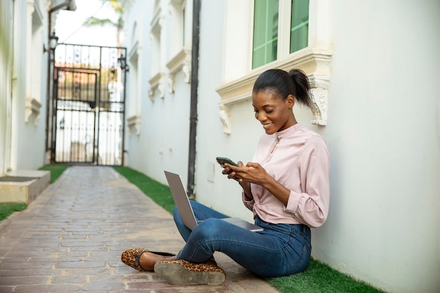 Happy black african woman typing message on device