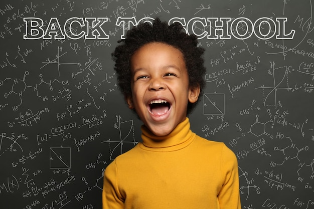 Happy black child screaming Back to school on chalkboard background