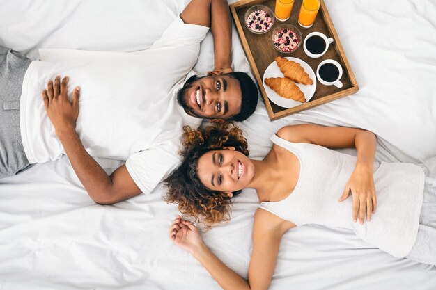 Foto una coppia di neri felici che si godono la colazione a letto.