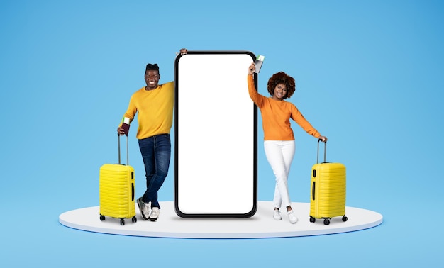 Happy black couple going vacation standing by huge phone