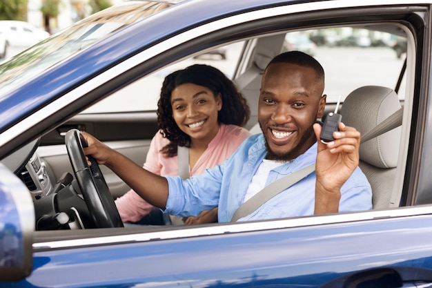 Happy black couple sitting in car showing keys