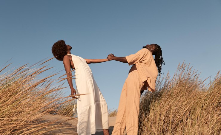 Photo happy black couple standing and holding hands between dry grass plants