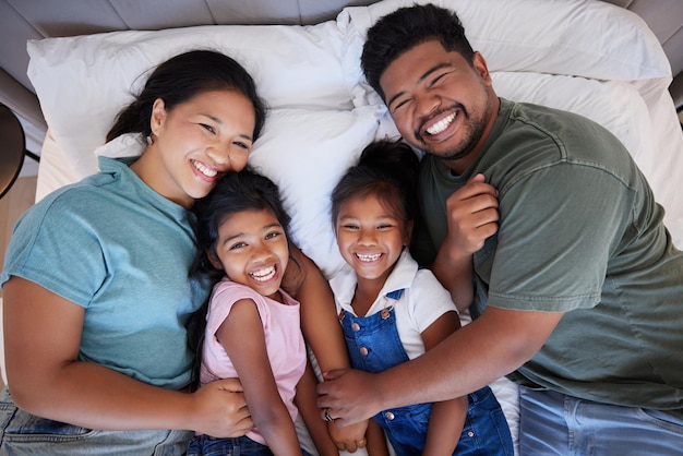 A happy black family in bed mom and dad hold children with love In their bedroom at home little kids laugh as parents hug them with a smile on their faces and enjoy the quality time home together