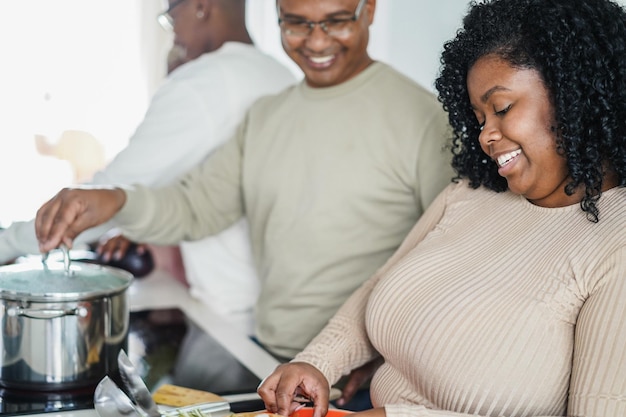 Felice famiglia nera che cucina all'interno della cucina a casa focus sul viso della ragazza