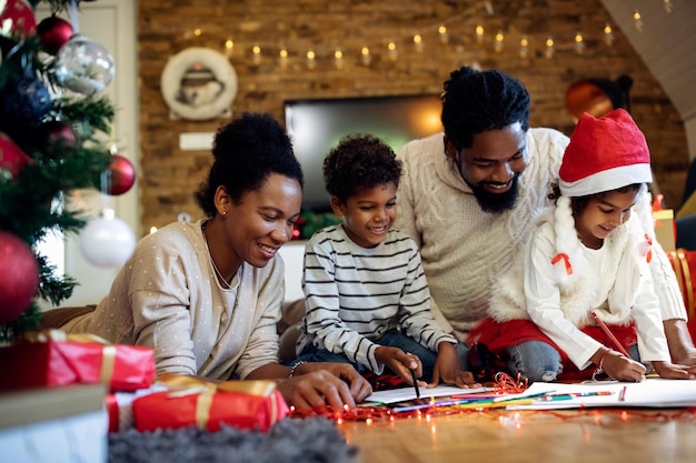 Happy black family enjoying while coloring during Christmas day at home