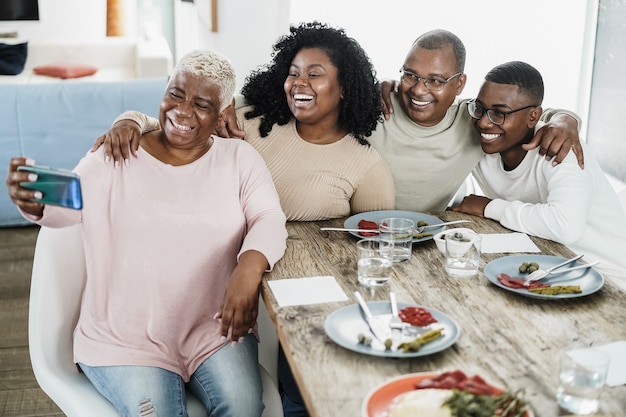 Счастливая черная семья, делающая селфи с мобильным телефоном дома
