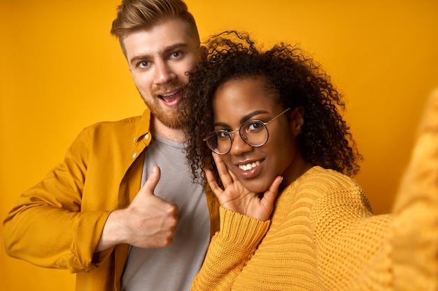 Happy black female and ginger male take selfie on smartphone smile and embrace cuddle each other