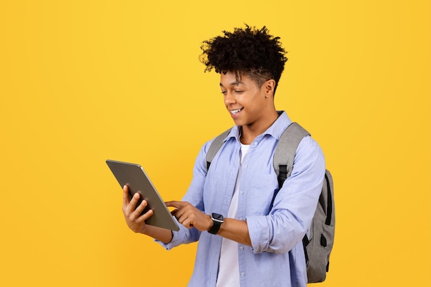 Happy black male student with tablet and backpack