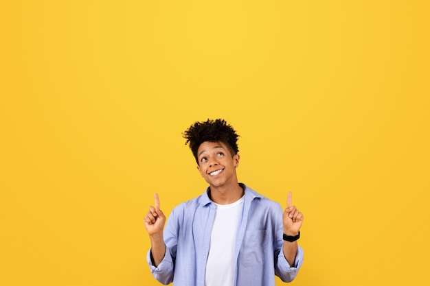 Photo happy black man points up at free space with both hands