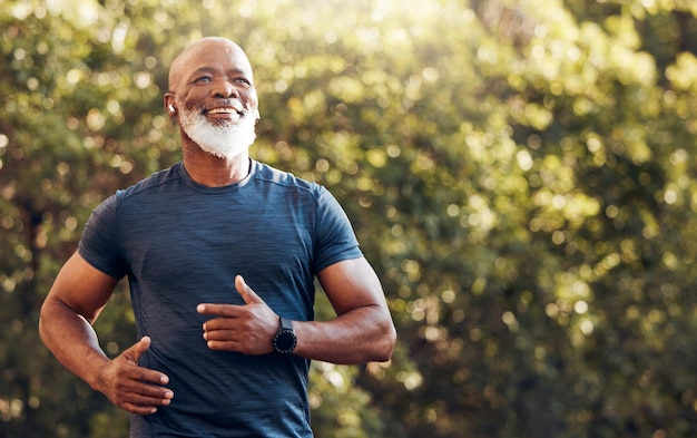 Happy black man running in park with music smile and mockup in nature garden and workout Senior male outdoor runner and motivation for fitness energy and healthy exercise training with earphones