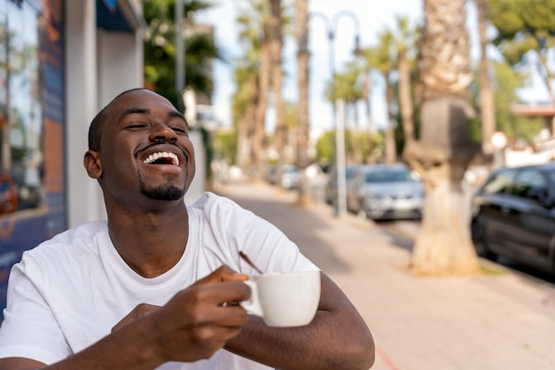 Happy black man with coffee in street cafe