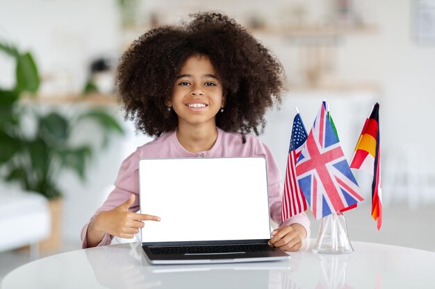 Happy black school girl schooler pointing at laptop mockup